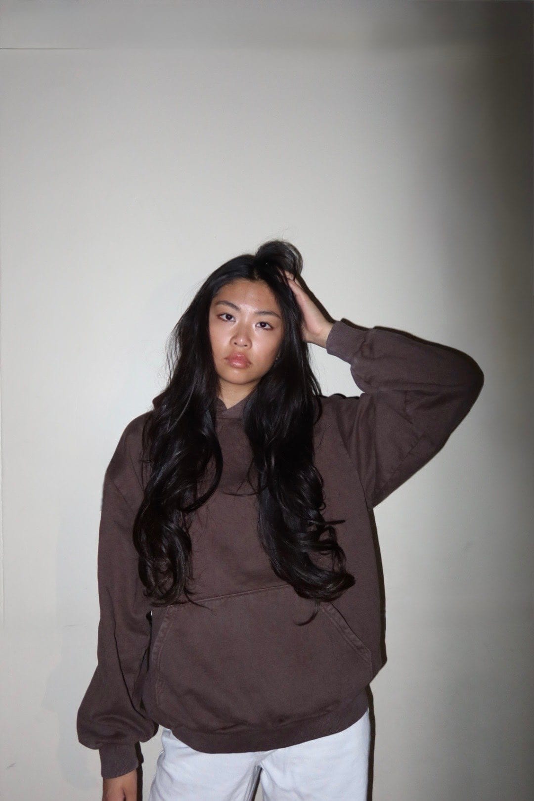 Blank burgundy crewneck sweatshirt worn front-facing against a white wall
